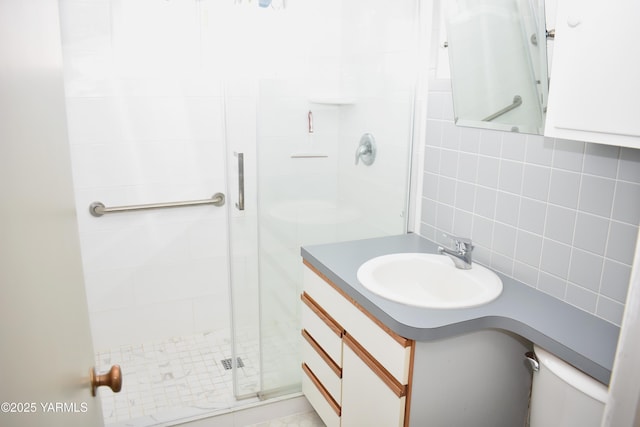 bathroom featuring decorative backsplash, a shower stall, tile walls, and vanity