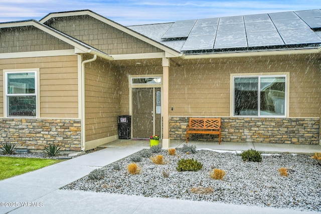 entrance to property featuring stone siding and solar panels