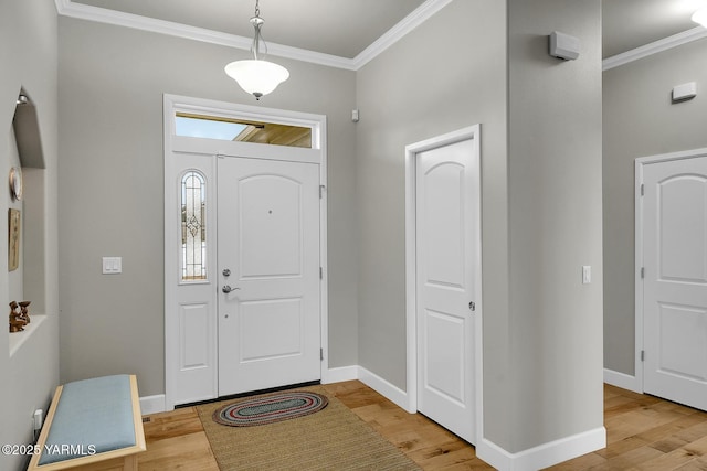 foyer featuring crown molding, baseboards, and wood finished floors