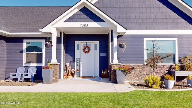 property entrance with a shingled roof and a yard