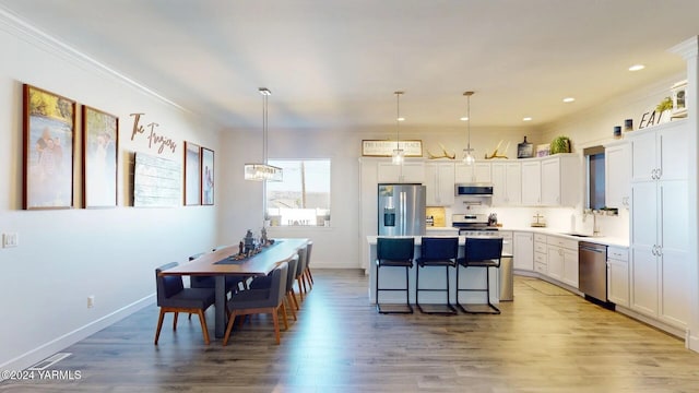 kitchen with pendant lighting, light countertops, appliances with stainless steel finishes, white cabinets, and a sink