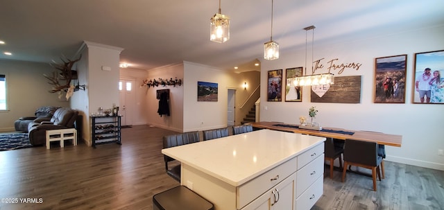 kitchen featuring dark wood-style flooring, white cabinetry, open floor plan, ornamental molding, and pendant lighting