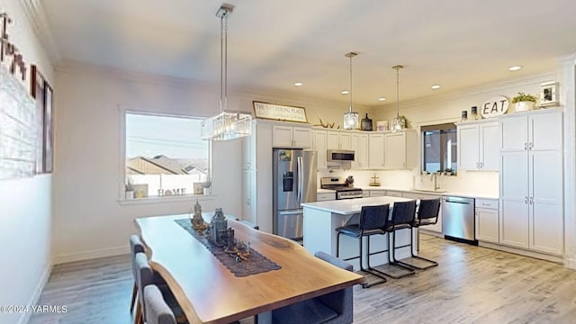 kitchen with a kitchen breakfast bar, a center island, stainless steel appliances, light countertops, and pendant lighting