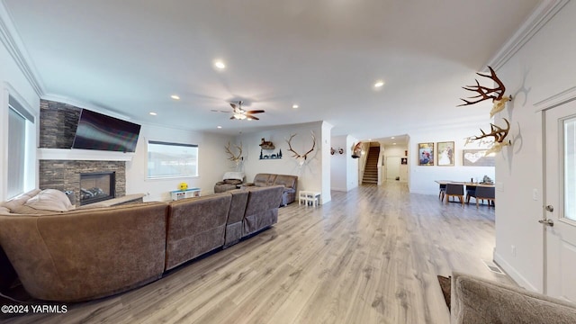 living area with a fireplace, crown molding, recessed lighting, stairway, and light wood-type flooring