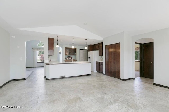 5304 Maui Pl, Yakima, WA 98908 - kitchen with arched walkways, white refrigerator with ice dispenser, dark brown cabinetry, light countertops, and vaulted ceiling