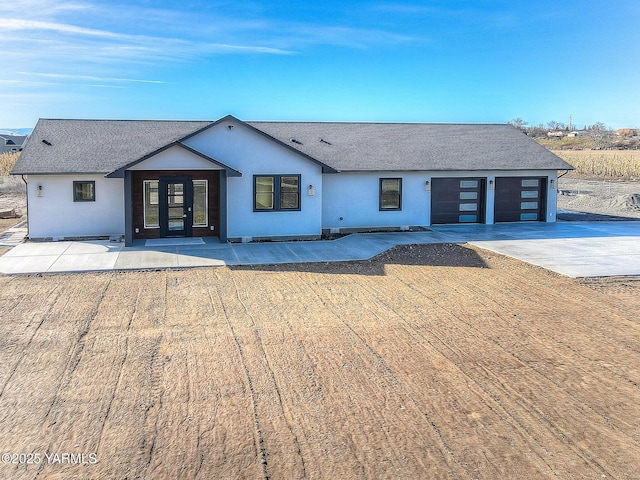 view of front facade with a garage, concrete driveway, a shingled roof, and stucco siding