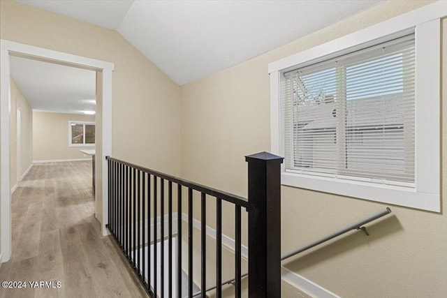 corridor with lofted ceiling, baseboards, light wood finished floors, and an upstairs landing