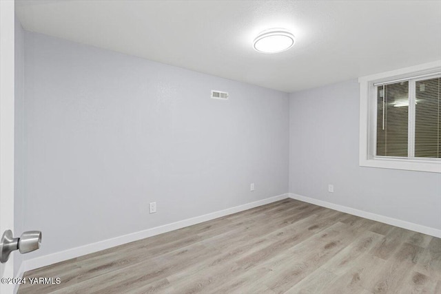 empty room featuring light wood-type flooring, visible vents, and baseboards