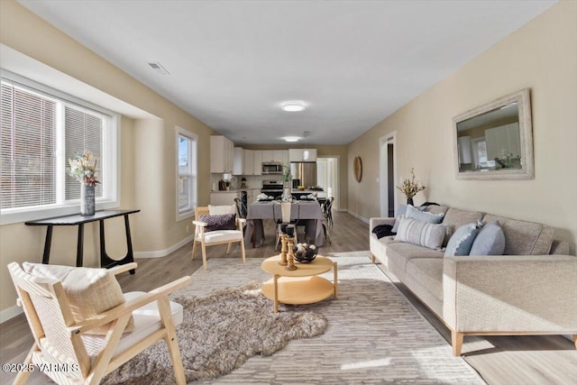 living area with baseboards, visible vents, and wood finished floors