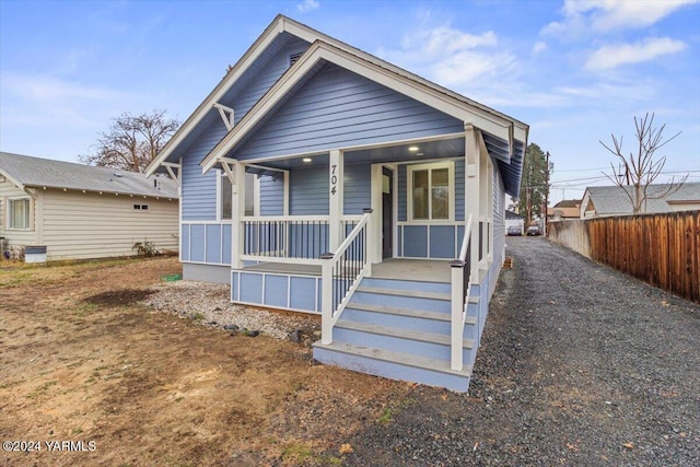 bungalow-style home with covered porch and fence