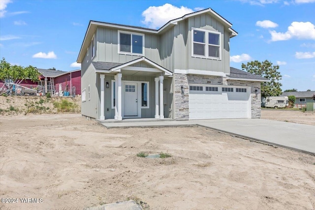 view of front facade featuring board and batten siding, stone siding, a garage, and concrete driveway