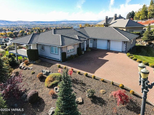 ranch-style home with a garage, decorative driveway, a tile roof, and stucco siding