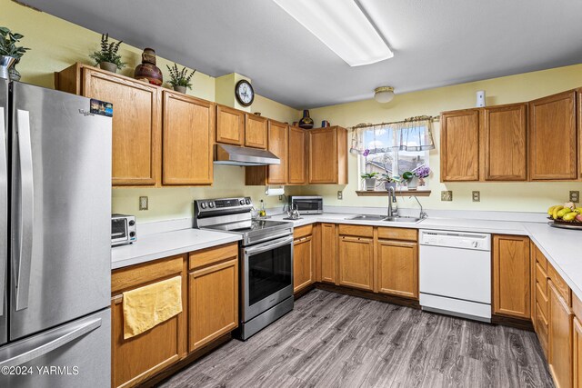 2705 Garrett St, Yakima, WA 98902 - kitchen featuring under cabinet range hood, stainless steel appliances, a sink, wood finished floors, and light countertops