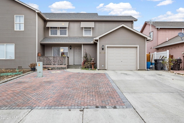 traditional-style home featuring decorative driveway, roof with shingles, and an attached garage