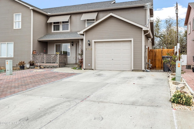 traditional home with concrete driveway, roof with shingles, and fence