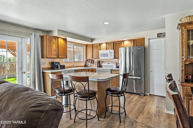 5502 Bristol Way, Yakima, WA 98908 - kitchen with a kitchen island, a breakfast bar, open floor plan, a textured ceiling, and appliances with stainless steel finishes