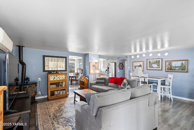 living area with dark wood-style floors, baseboards, a wood stove, and a wall unit AC