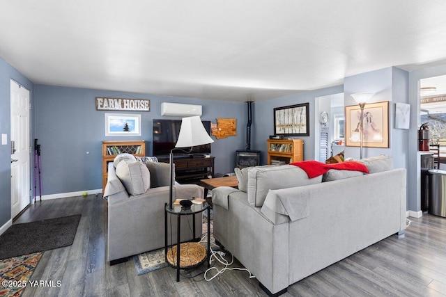 living area with baseboards, an AC wall unit, wood finished floors, and a wood stove