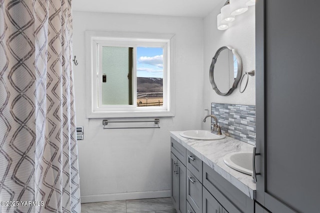 full bathroom featuring a sink, decorative backsplash, baseboards, and double vanity