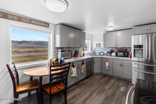 kitchen featuring black appliances, gray cabinetry, dark wood-style floors, light countertops, and decorative backsplash