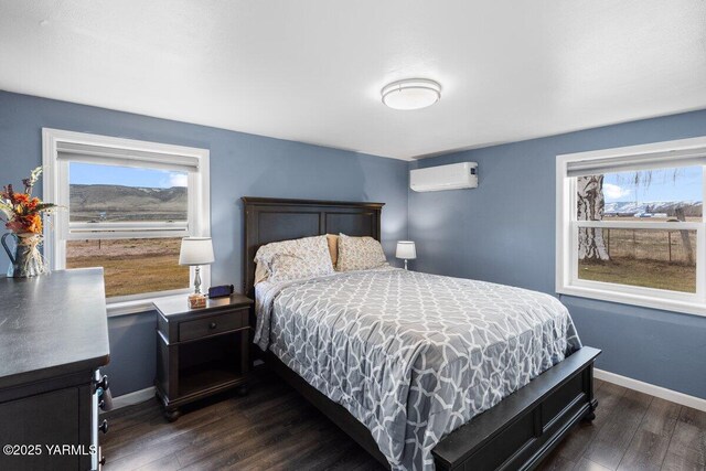 bedroom with dark wood finished floors, multiple windows, and a wall unit AC