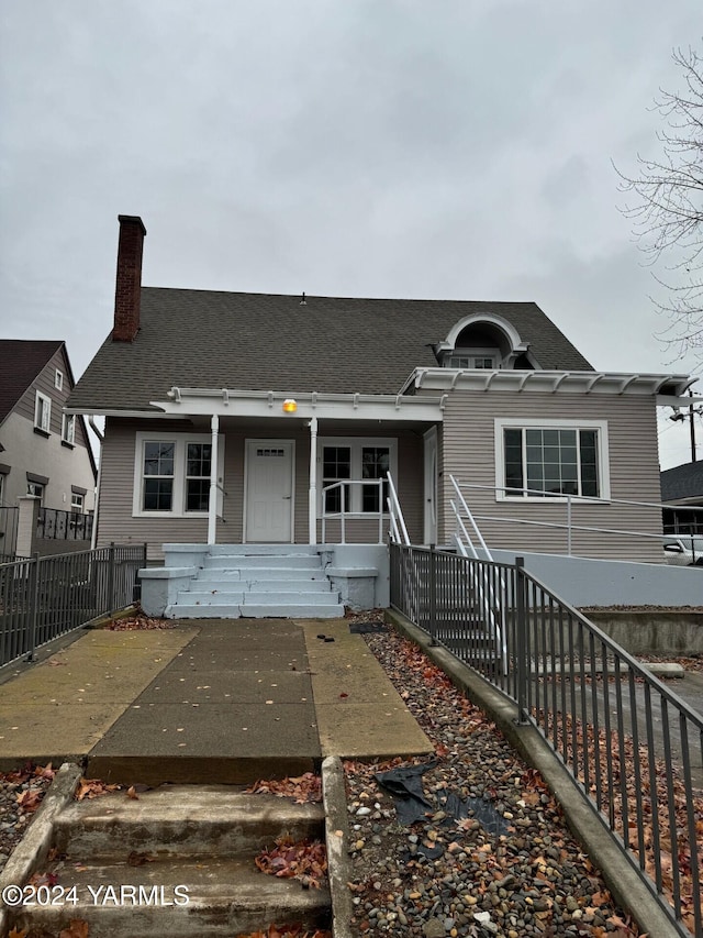 view of front of home featuring a porch, fence, and a chimney