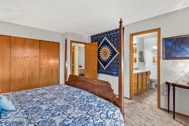 bedroom with light carpet, a closet, baseboards, and ensuite bathroom
