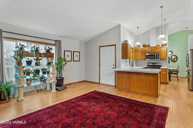 kitchen with light wood finished floors, appliances with stainless steel finishes, brown cabinets, a peninsula, and light countertops