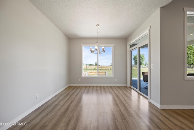 172004 NW Dogwood Rd, Prosser, WA 99350 - unfurnished dining area with wood finished floors, a chandelier, a textured ceiling, and baseboards