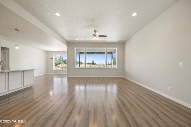 172004 NW Dogwood Rd, Prosser, WA 99350 - unfurnished living room with a textured ceiling, plenty of natural light, ceiling fan, baseboards, and light wood finished floors