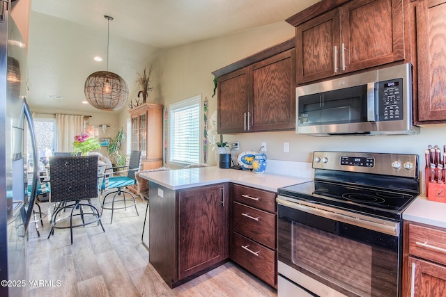 310 S 12th St, Selah, WA 98942 - kitchen with stainless steel appliances, light wood-style floors, a peninsula, light countertops, and hanging light fixtures
