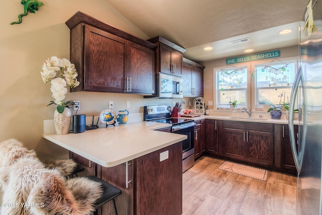 310 S 12th St, Selah, WA 98942 - kitchen featuring appliances with stainless steel finishes, a peninsula, light wood-style flooring, a kitchen breakfast bar, and light countertops