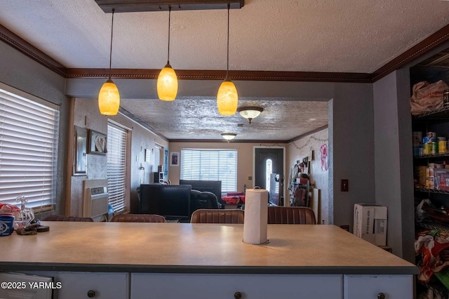 kitchen featuring decorative light fixtures, ornamental molding, open floor plan, a textured ceiling, and white cabinetry