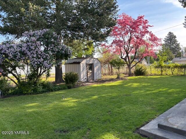 view of yard with a storage shed, fence, and an outbuilding