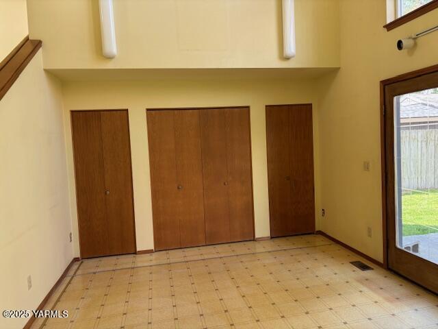 foyer entrance with light floors, a towering ceiling, and visible vents