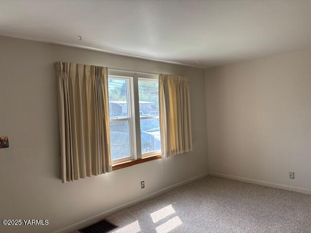 carpeted spare room with baseboards and visible vents