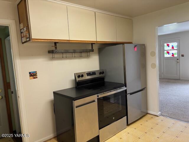 kitchen featuring dark countertops, light floors, baseboards, and stainless steel appliances