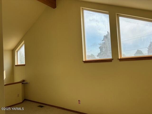 additional living space with baseboards, visible vents, and vaulted ceiling with beams