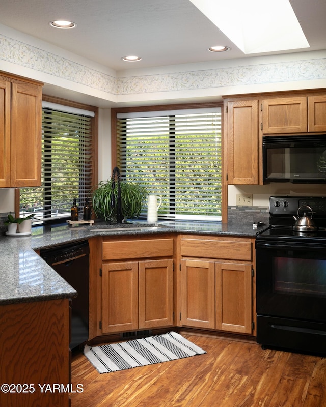 101 N 48th Ave Unit 31A, Yakima, WA 98908 - kitchen featuring black appliances, wood finished floors, healthy amount of natural light, and brown cabinets