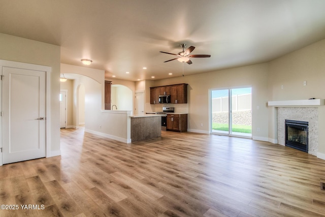 302 N 90th Ave, Yakima, WA 98908 - unfurnished living room with arched walkways, ceiling fan, light wood-type flooring, a glass covered fireplace, and recessed lighting
