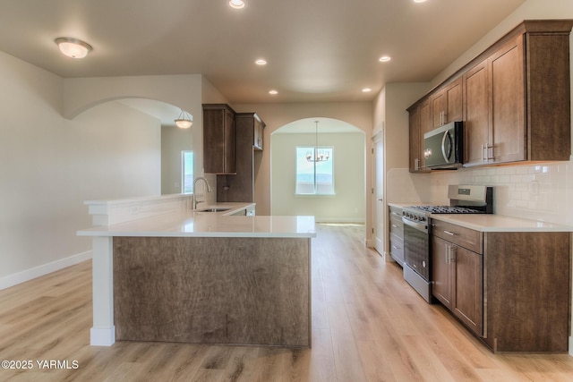 302 N 90th Ave, Yakima, WA 98908 - kitchen with stainless steel appliances, arched walkways, a peninsula, light wood-style floors, and recessed lighting