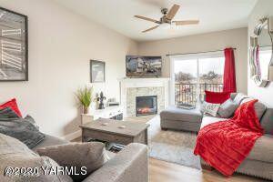 living area with ceiling fan, a lit fireplace, and wood finished floors