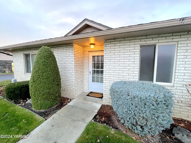 property entrance with board and batten siding and brick siding