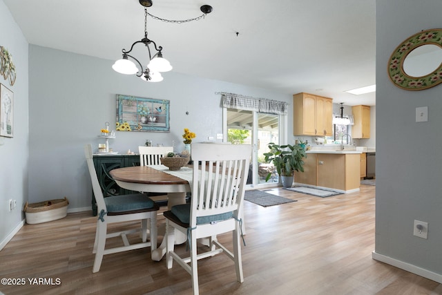 dining area featuring light wood-style flooring, a chandelier, and baseboards