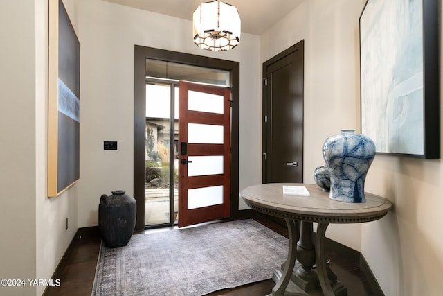 entrance foyer featuring a chandelier, dark wood finished floors, and baseboards