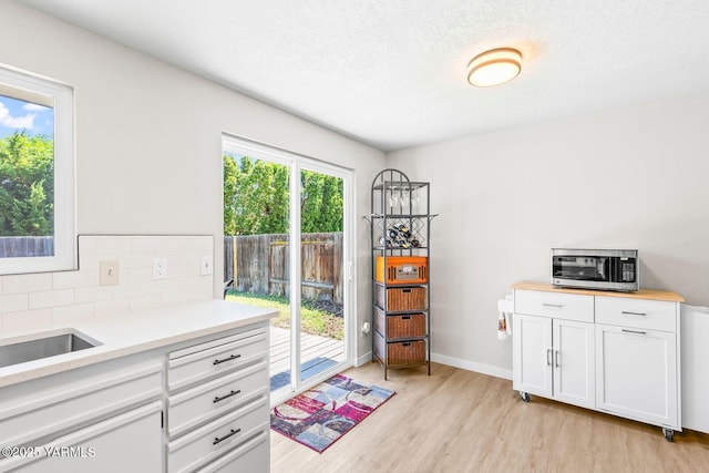 1805 S 66th Ave, Yakima, WA 98908 - kitchen featuring stainless steel microwave, light wood finished floors, light countertops, white cabinetry, and a textured ceiling