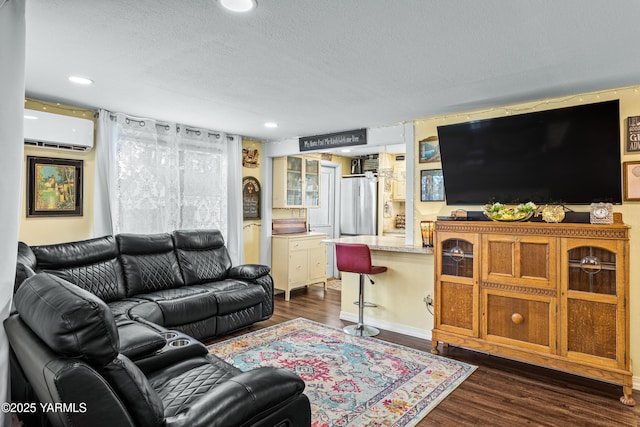 living room with an AC wall unit, recessed lighting, dark wood-type flooring, and a textured ceiling