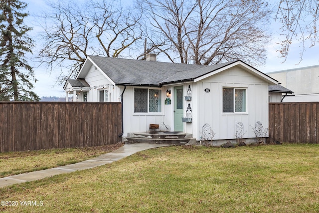 view of front of property with a front yard, fence, a shingled roof, a chimney, and board and batten siding