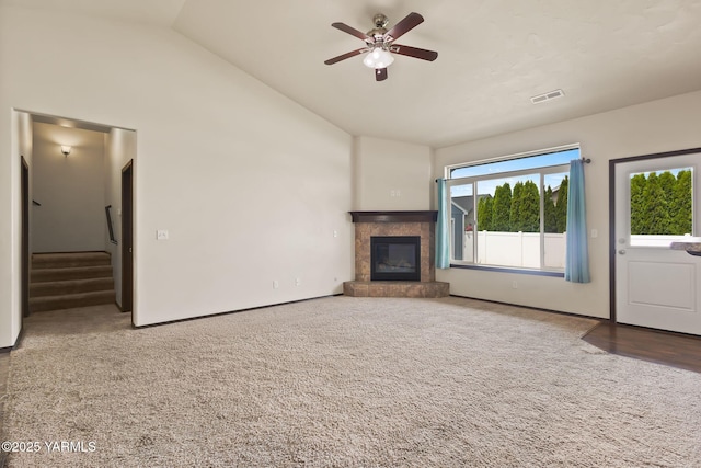 5901 Coolidge Rd, Yakima, WA 98903 - unfurnished living room featuring carpet floors, a ceiling fan, a tile fireplace, high vaulted ceiling, and stairway