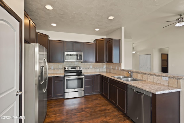 5901 Coolidge Rd, Yakima, WA 98903 - kitchen with appliances with stainless steel finishes, a peninsula, decorative backsplash, dark brown cabinetry, and dark wood-style floors